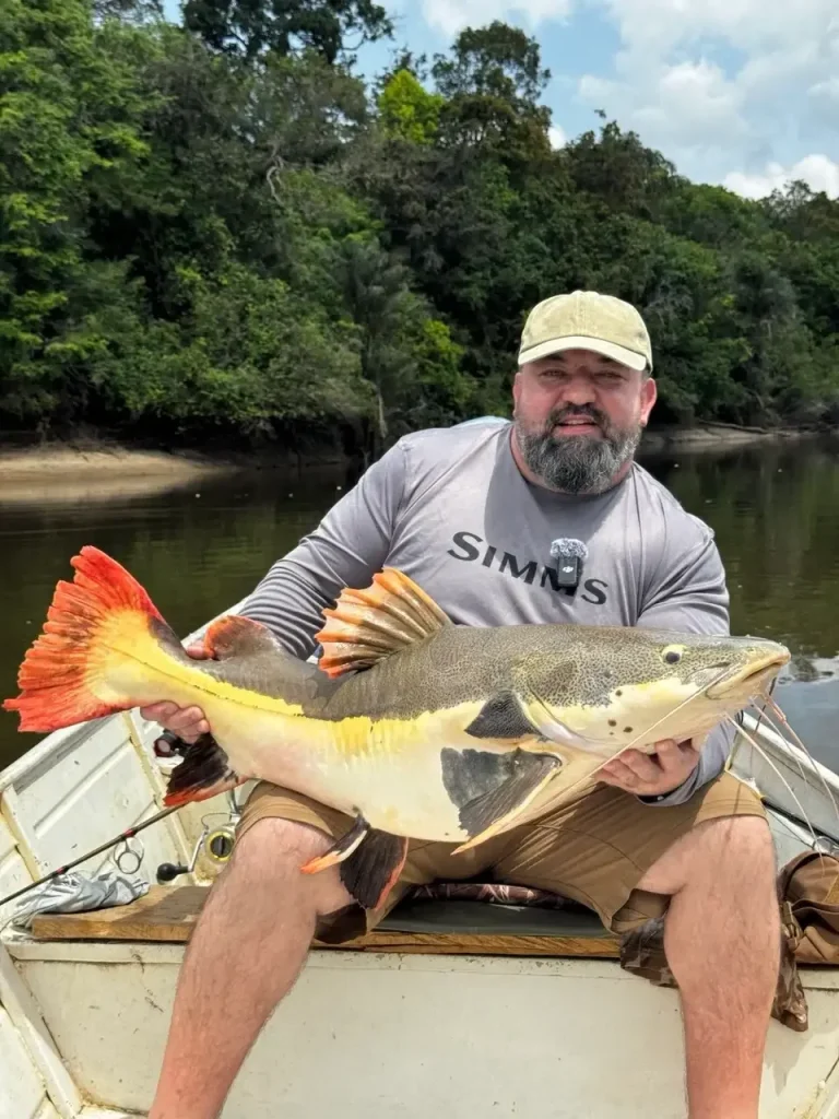 垂釣者手持在圭亞那垂釣之旅中釣獲的鯰魚