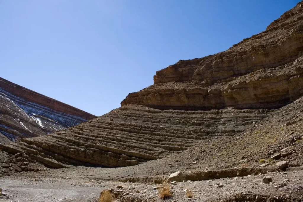 Layered sedimentary rock formations on a canyon wall under a blue sky